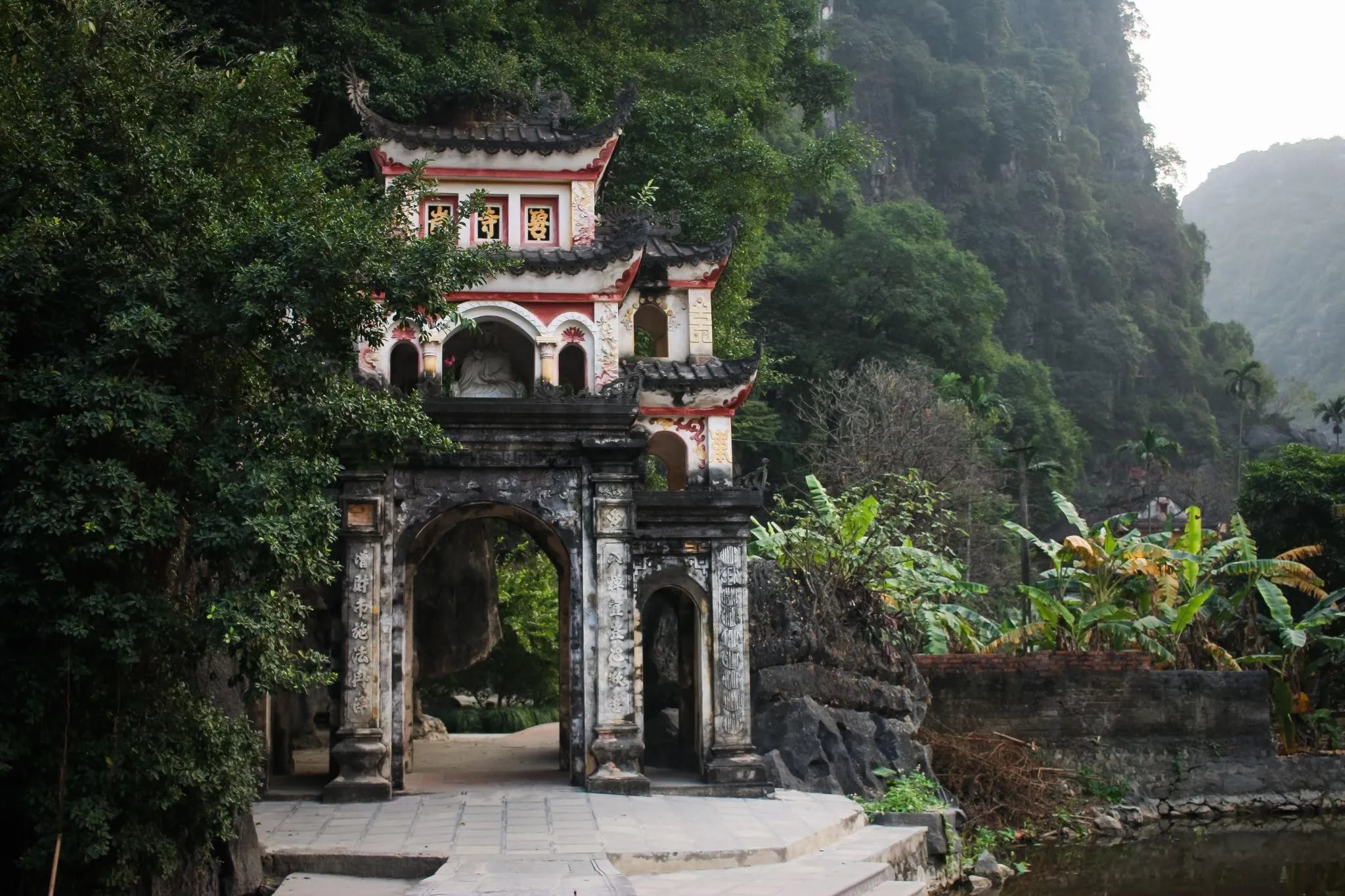 Bich Dong Pagoda in winter is shrouded in a gentle chill, with mist curling around ancient stone steps and moss-covered roofs